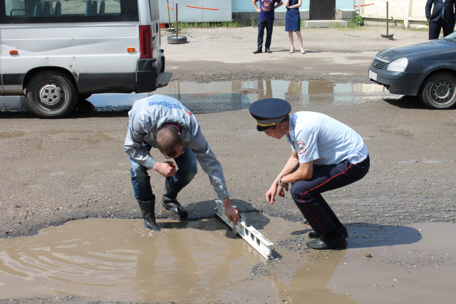 Активист и сотрудник ГИБДД замеряют ямы. Фото: onf.ru